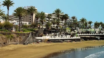 Ein Strandhotel mit Palmen, einem Poolbereich und einer Treppe zum Strand.