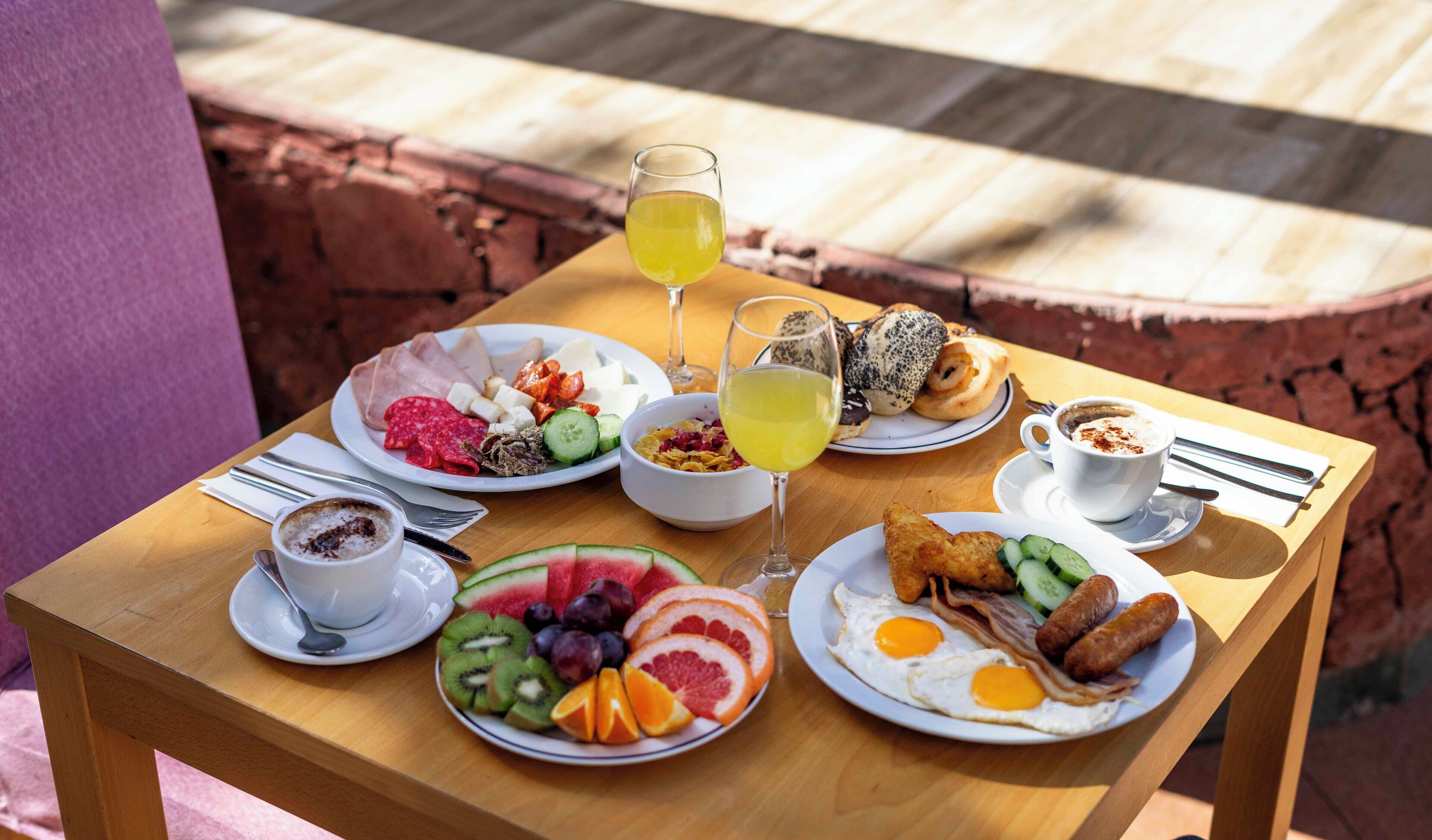 Une table de petit-déjeuner avec des assiettes de nourriture, un verre de jus de fruits et une tasse de café.
