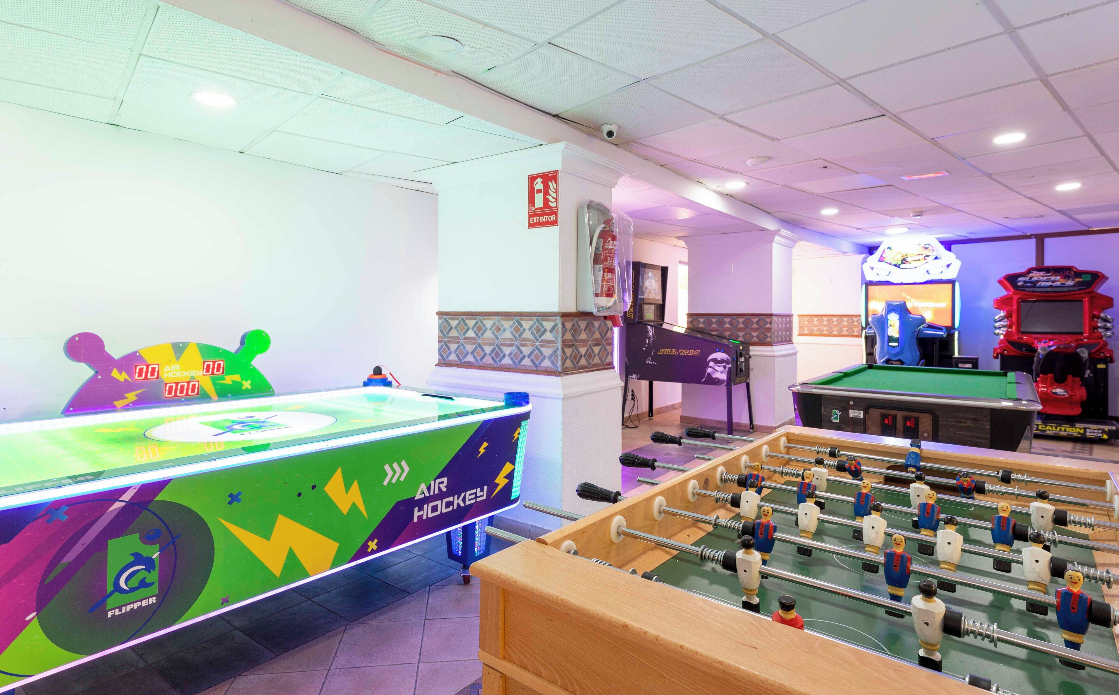 Une pièce équipée d’un baby-foot, d’une table de billard et d’une table de hockey aux couleurs vives.