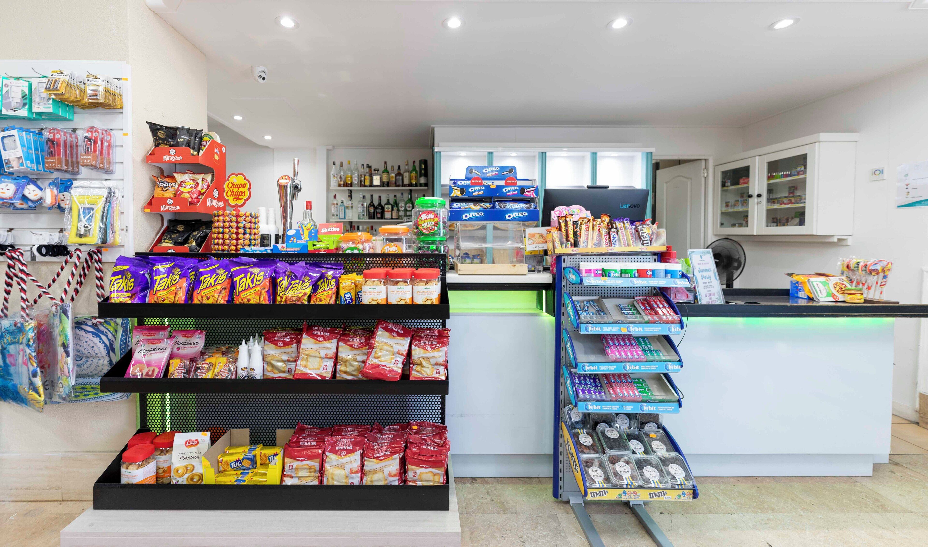Un kiosque proposant des collations et des boissons, avec un assortiment de produits emballés, ainsi qu'une caisse enregistreuse.