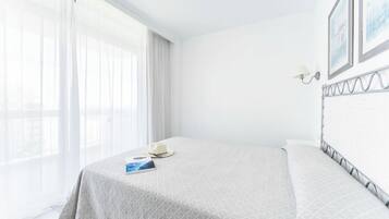 Un lit bien fait, recouvert d’une couvre-lit à motifs, avec un livre et un chapeau posés dessus.