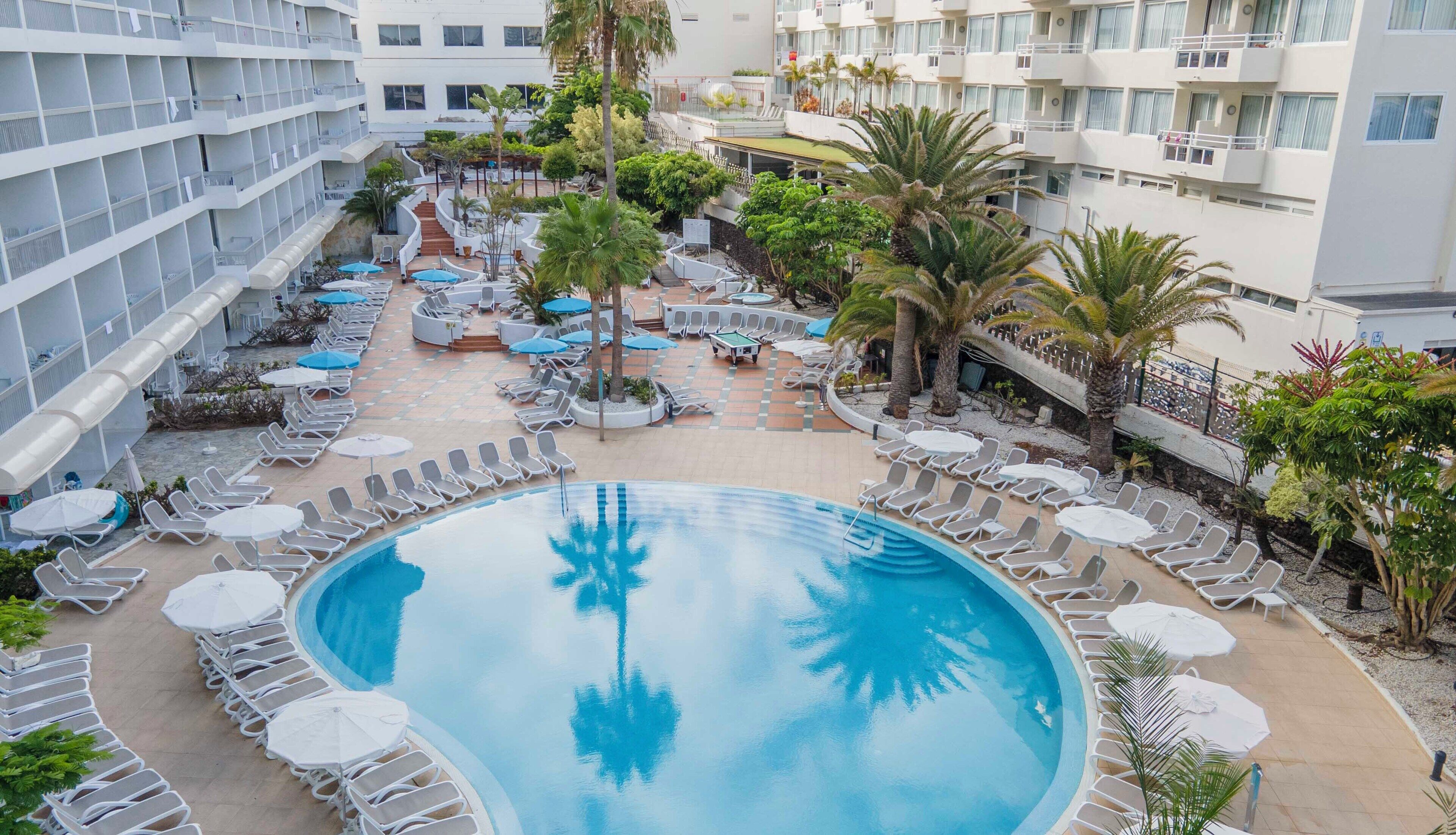 Una piscina al aire libre, sillones reclinables de piscina
