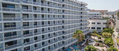 A multi-story hotel with balconies, outdoor seating, and a pool area.
