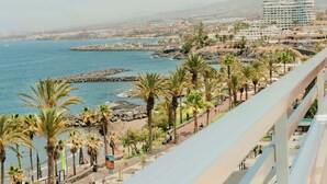 A coastal cityscape with a prominent hotel and a rocky breakwater.