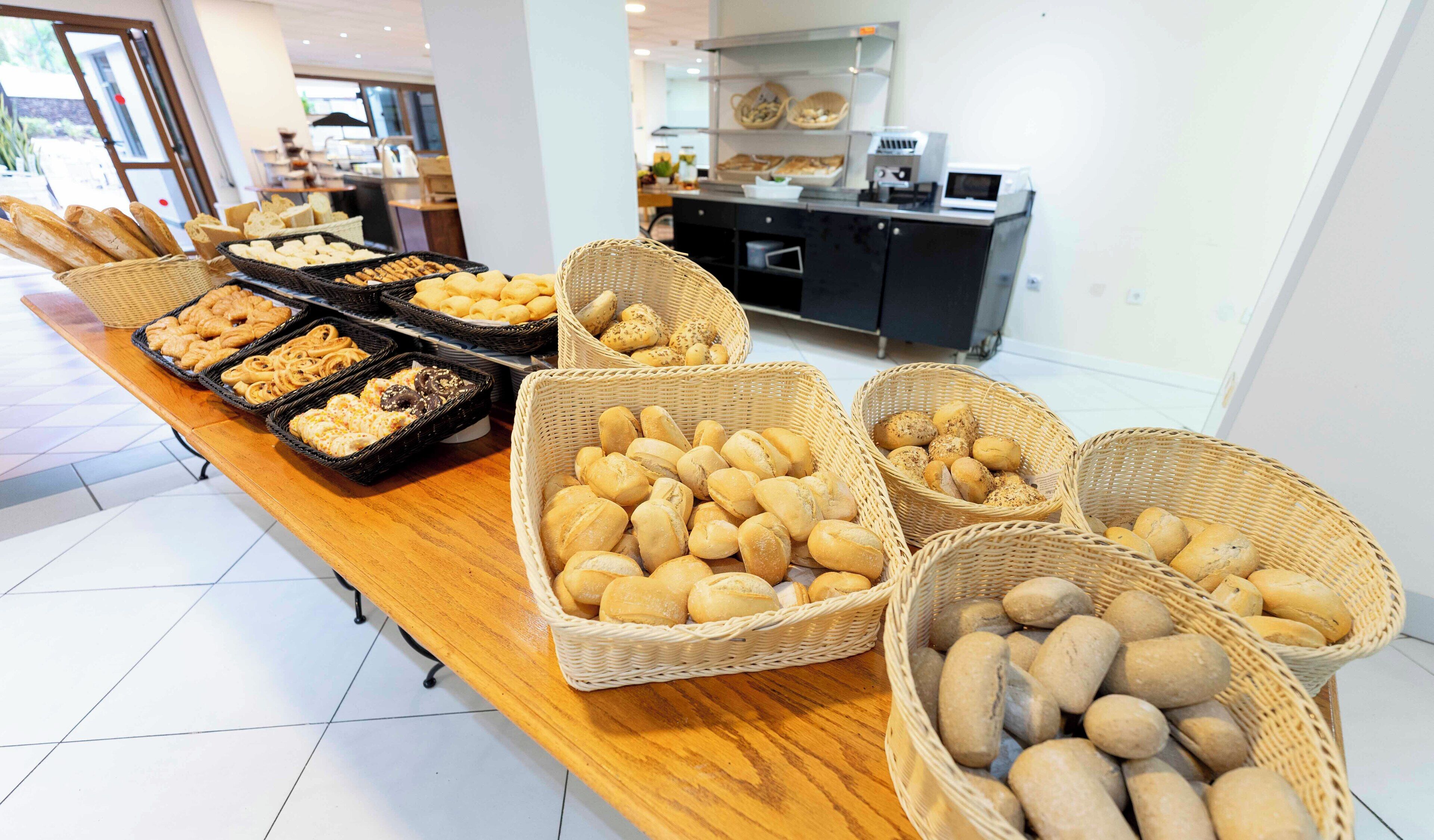 A buffet table with various bread and pastries in baskets.
