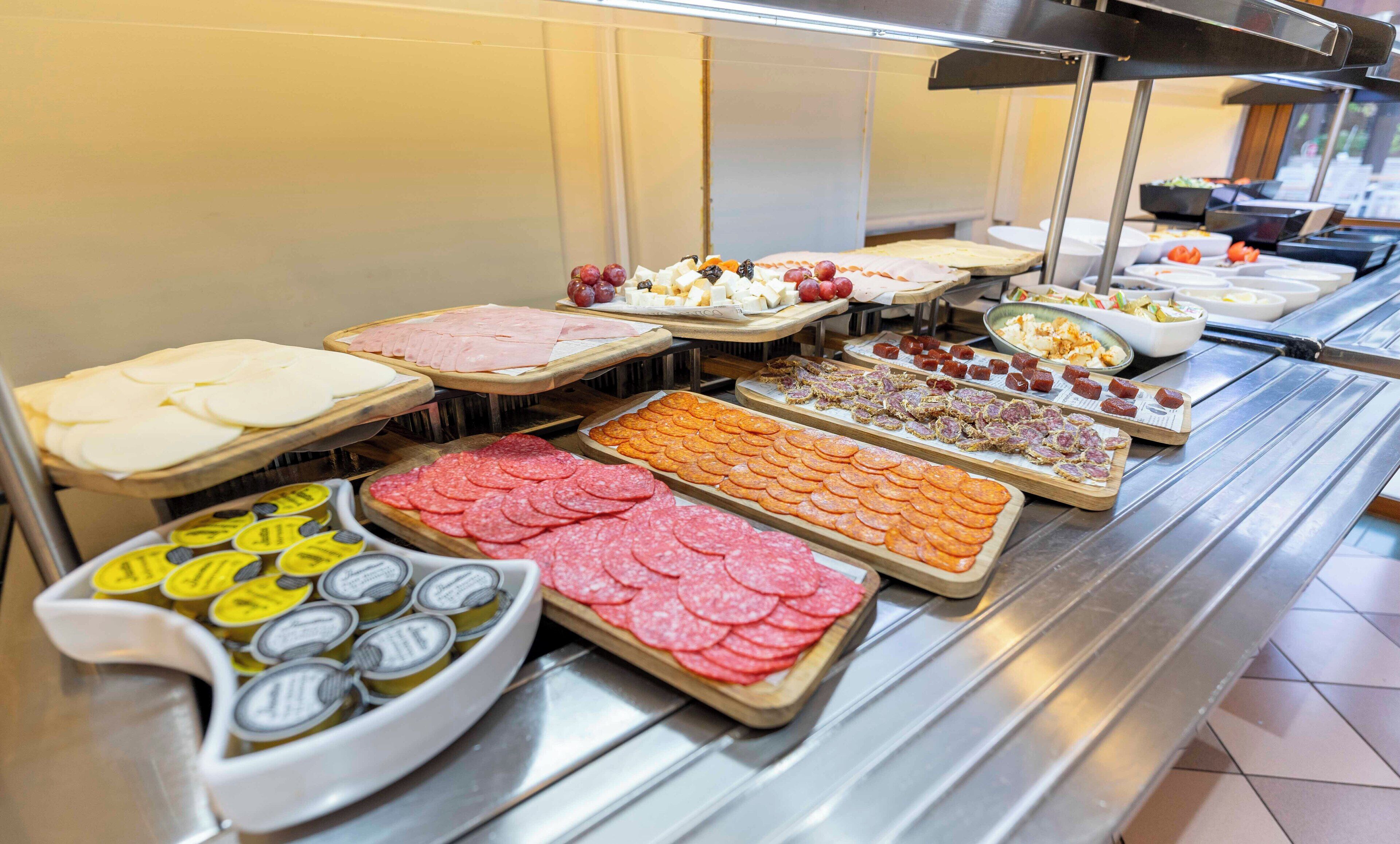 A buffet with various food items including sliced meats, cheeses, and fruits.