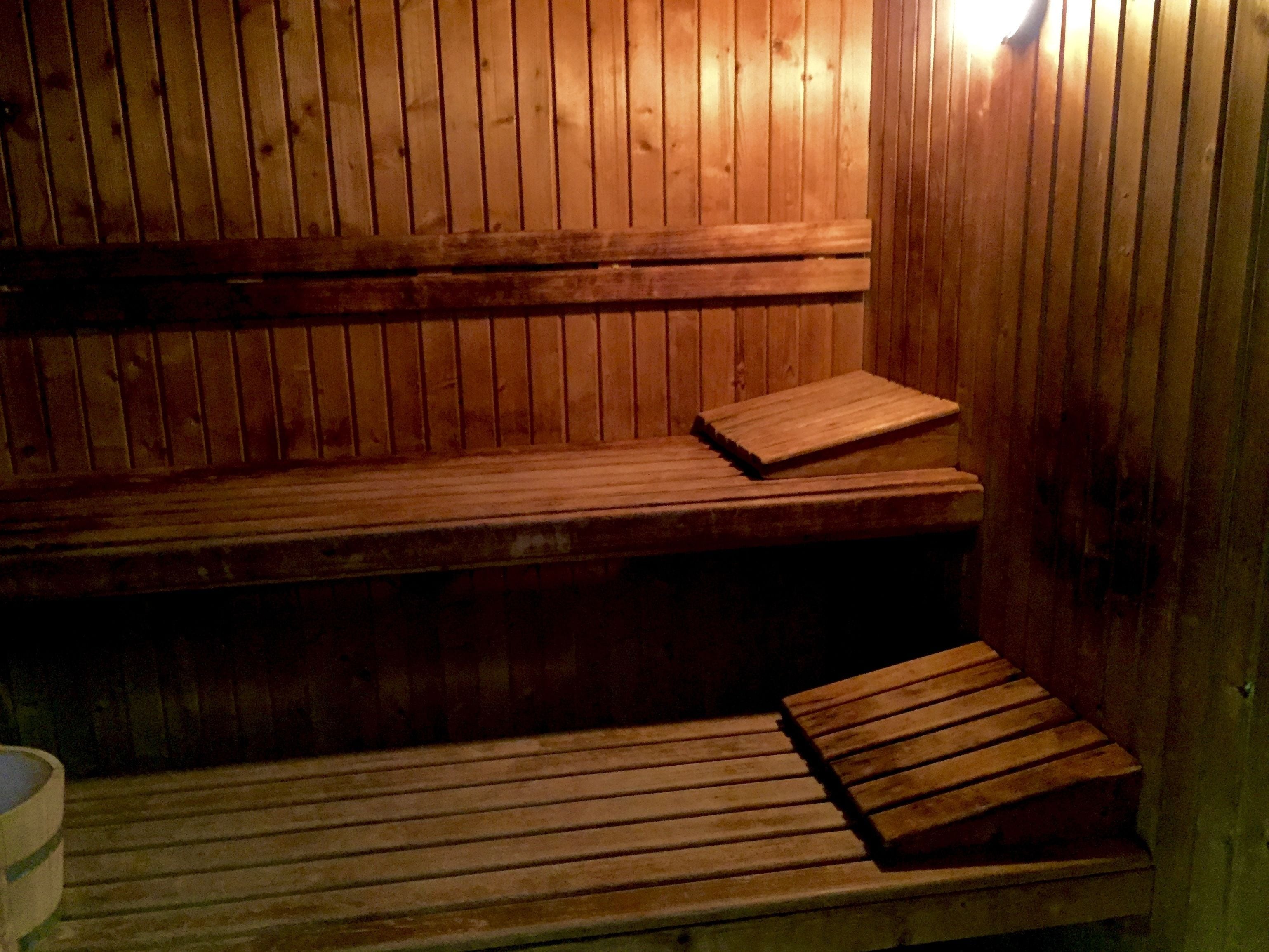 Una sauna de madera con bancos y un asiento tipo banca.