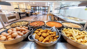 A buffet with various food items including eggs, mushrooms, beans, soup, and pasta.