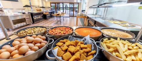 Een buffet met diverse gerechten, waaronder eieren, paddenstoelen, bonen, soep en pasta.