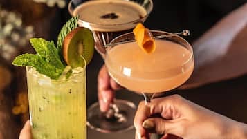 Two people holding cocktail glasses with garnishes.