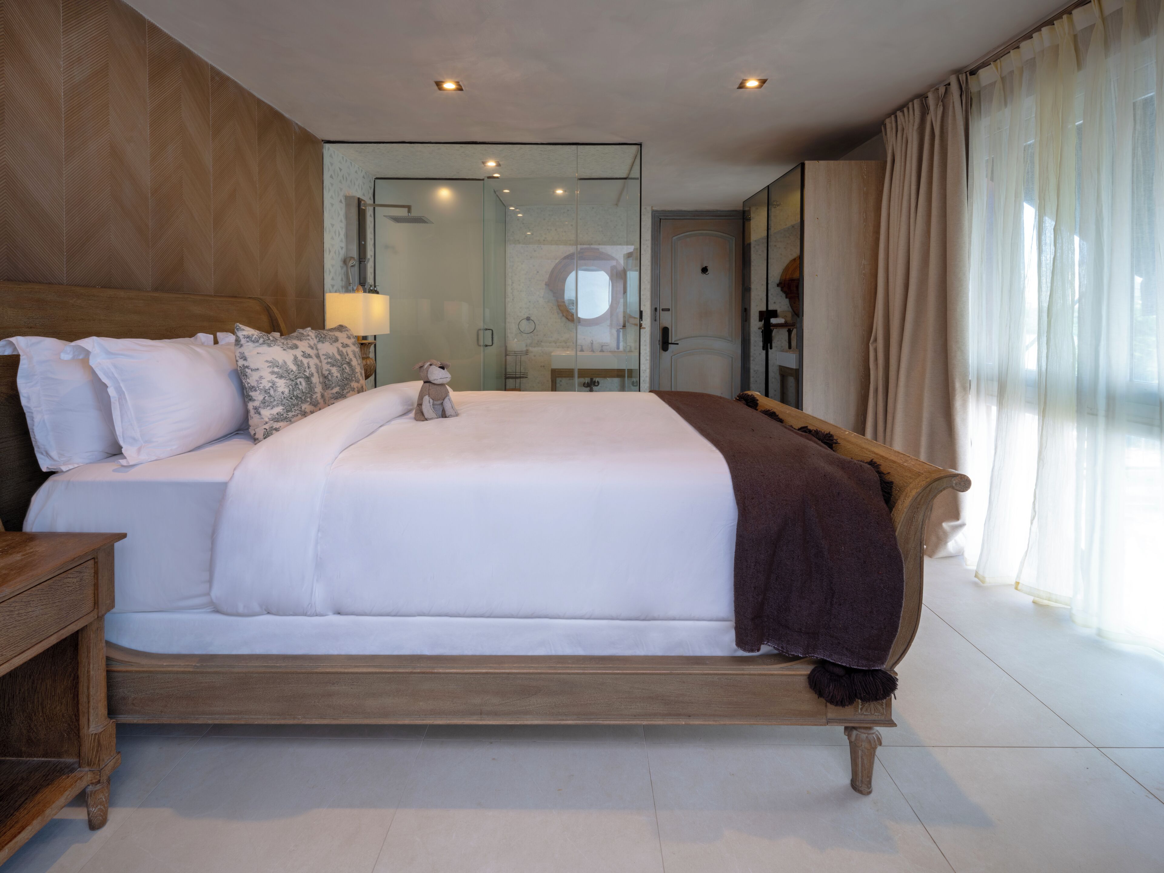 A large bed with a wooden headboard, a nightstand, and a plush toy.