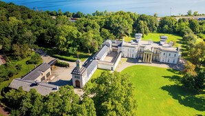 An aerial view of a large, historic estate with multiple buildings, expansive lawns, and a lake in the background. - Staybridge Suites Hamilton Downtown by IHG (Hamilton)