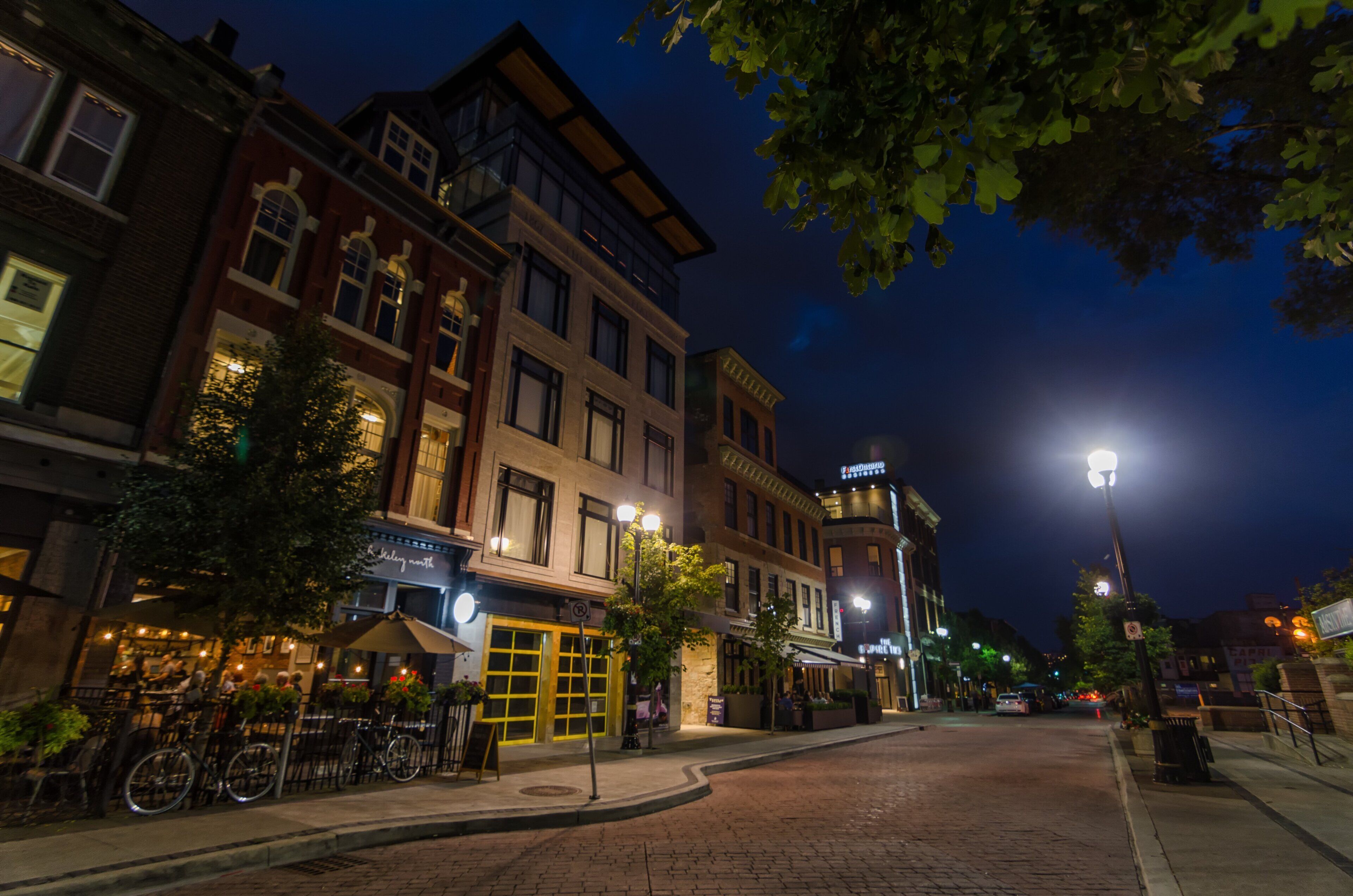 A nighttime street view with buildings, bicycles, and street lamps.