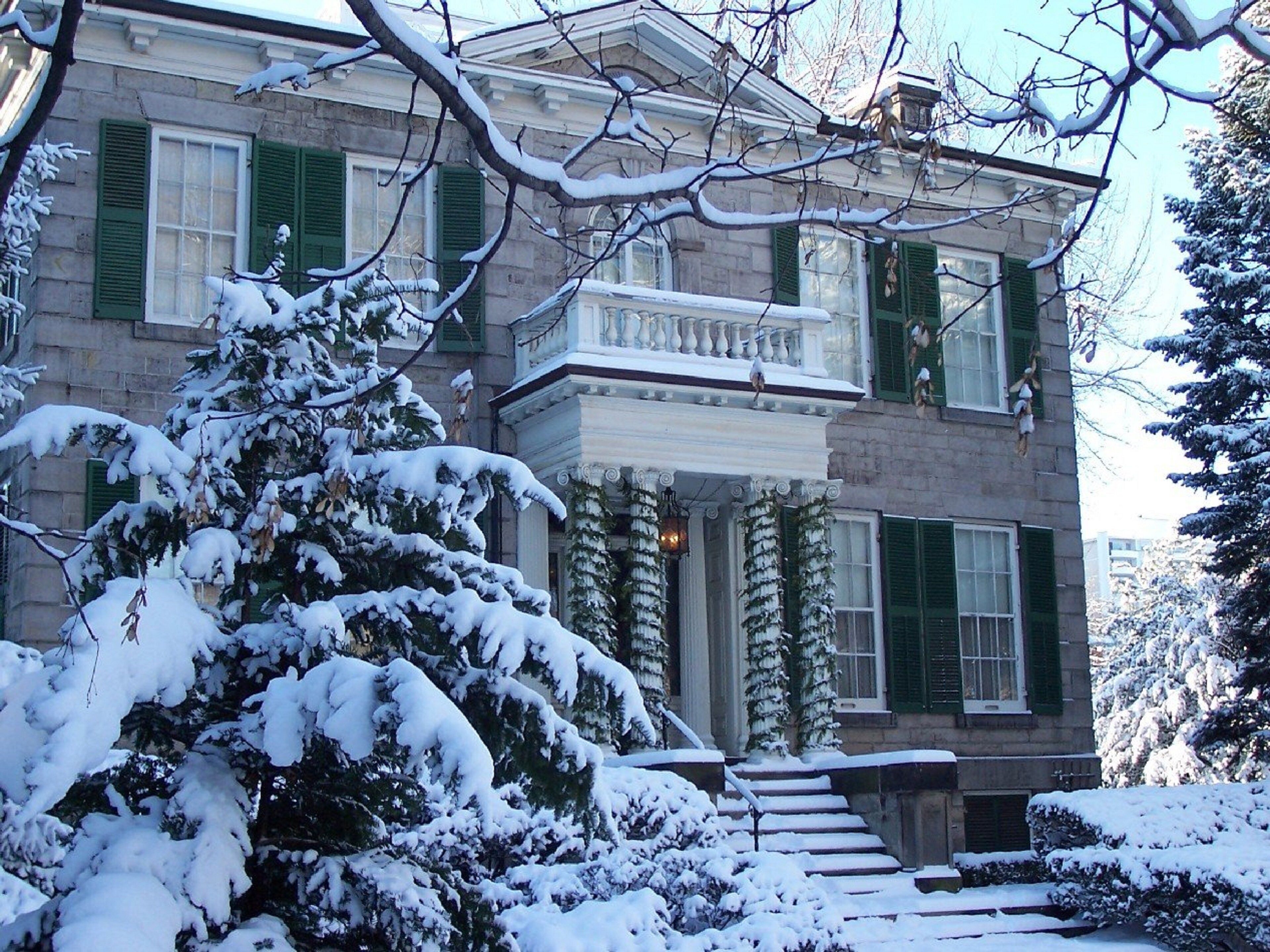 A two-story house with a snow-covered front yard and a balcony.