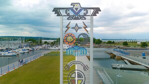 A marina with boats docked, a large decorative structure, and a bridge over water.