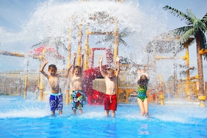Area giochi con acqua, dove bambini si divertono con uno scivolo e un’area spruzzi.