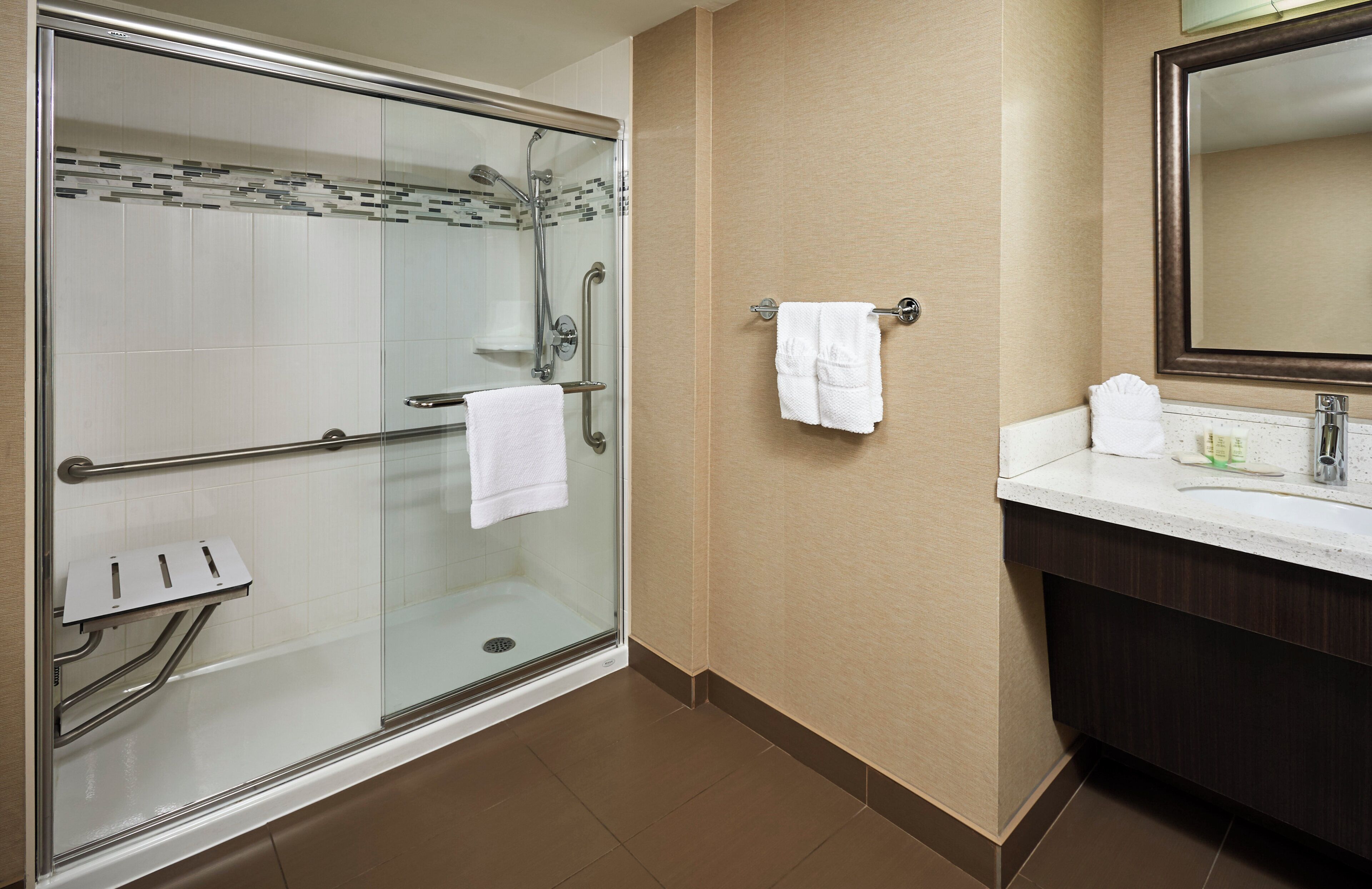 Une salle de bain moderne avec une douche à parois de verre, un meuble-lavabo avec un miroir et un porte-serviettes.