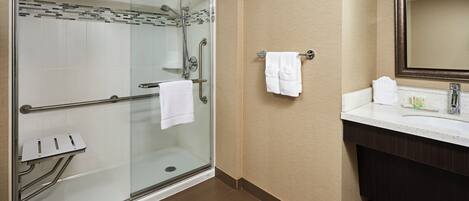 Une salle de bain moderne avec une douche à parois de verre, un meuble-lavabo avec un miroir et un porte-serviettes.