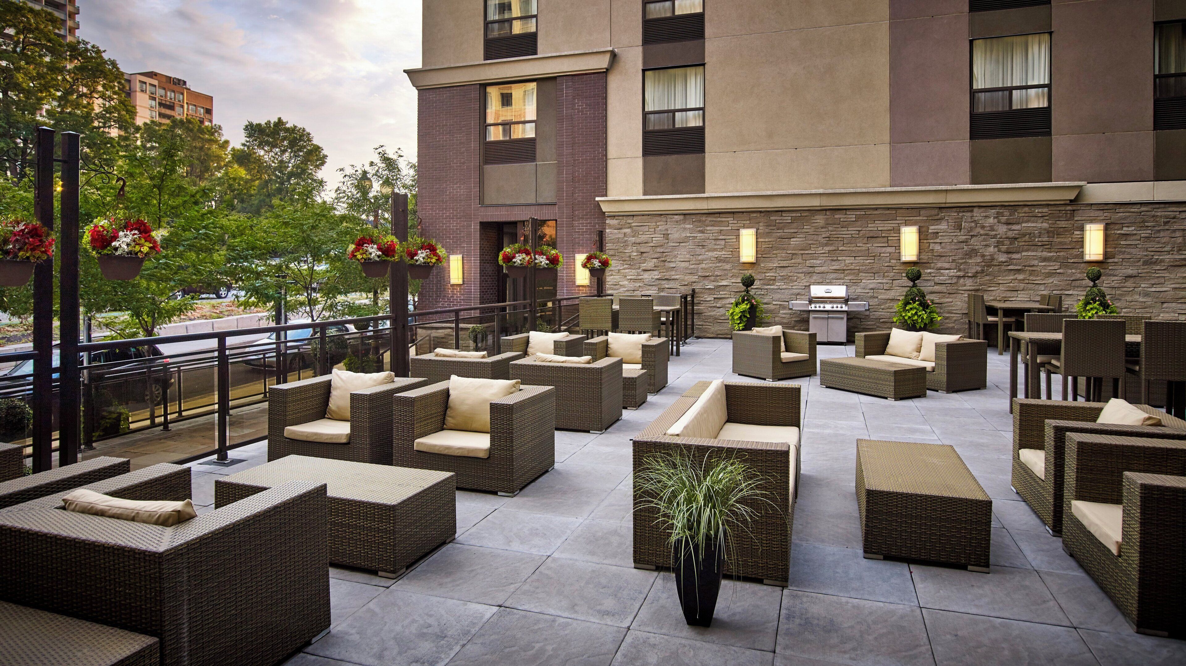 An outdoor patio with wicker furniture and potted plants.