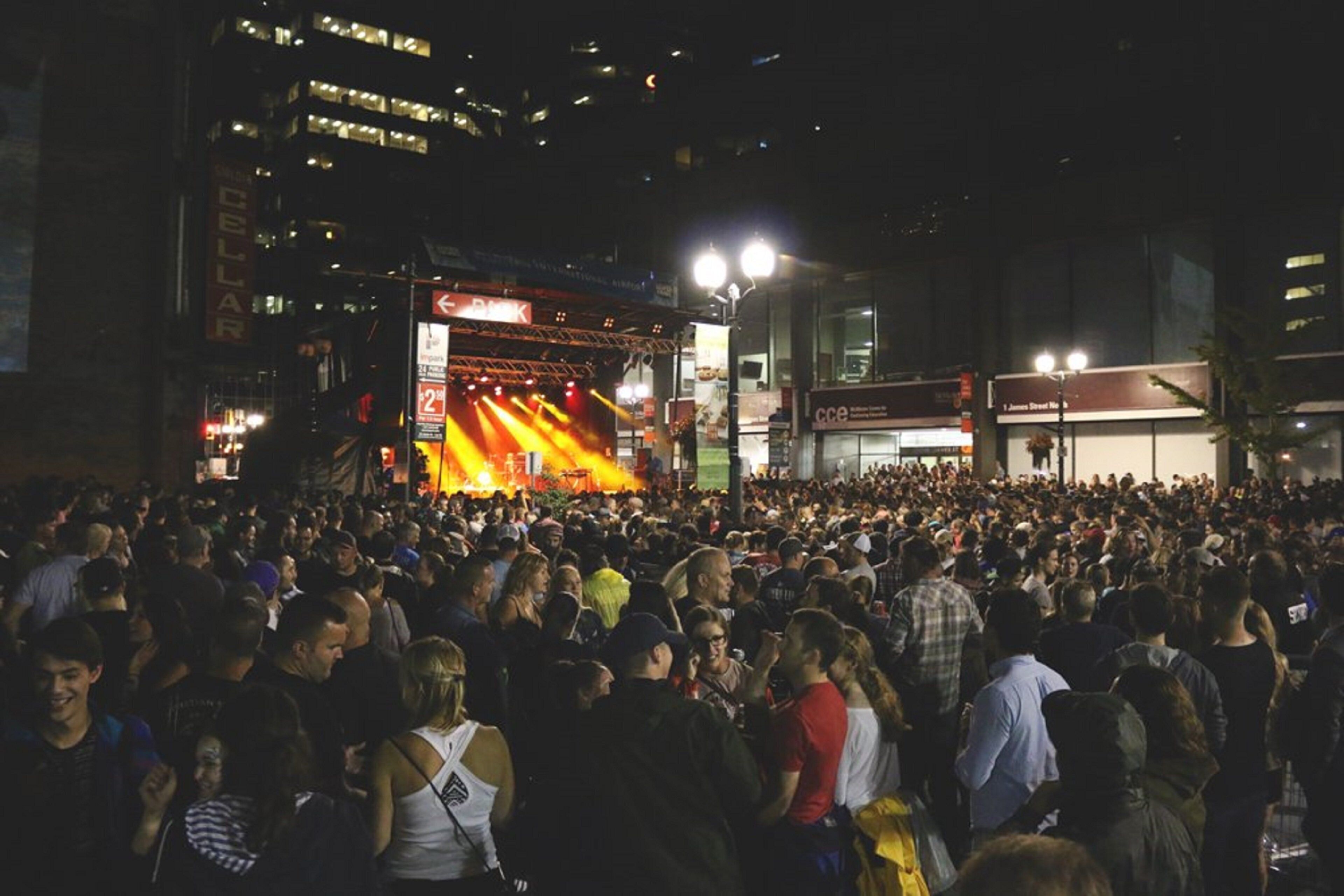 A crowded outdoor event with a stage and audience.