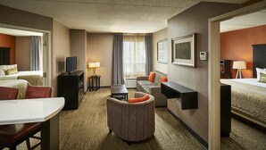 A hotel room with a bed, a sofa, a dining table, and a small seating area.