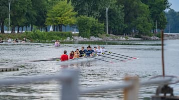 A rowing team in a boat on a calm lake with trees in the background.