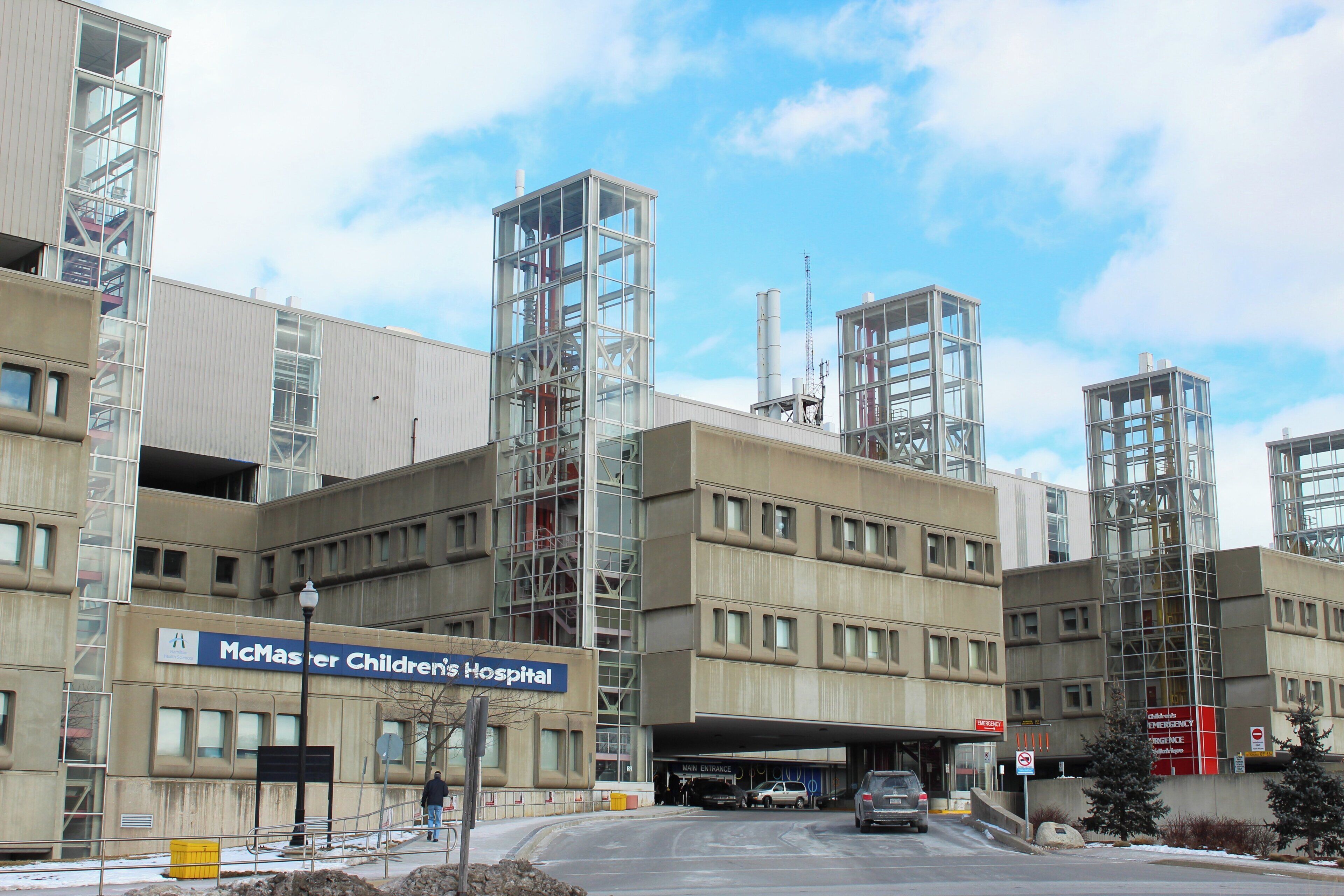 A hospital building with multiple floors, emergency signs, and a clear sky.