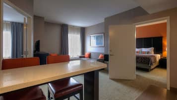 Una habitación de hotel con comedor, sofá, cama y televisor.