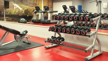Un gimnasio con cintas de correr, mancuernas y un banco.