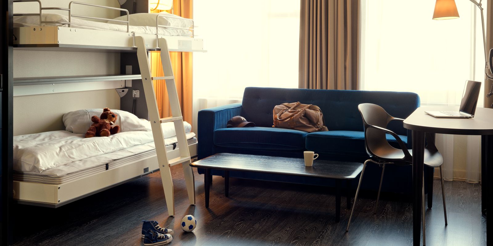 Une pièce avec des lits superposés, un canapé, une table basse et un bureau avec un ordinateur portable.