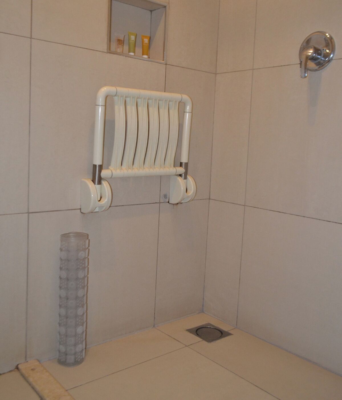 Un baño con toallero blanco, un espejo y desagüe de ducha.