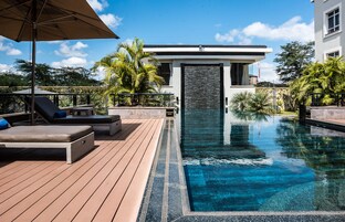 Una piscina al aire libre, sombrillas, sillones reclinables de piscina