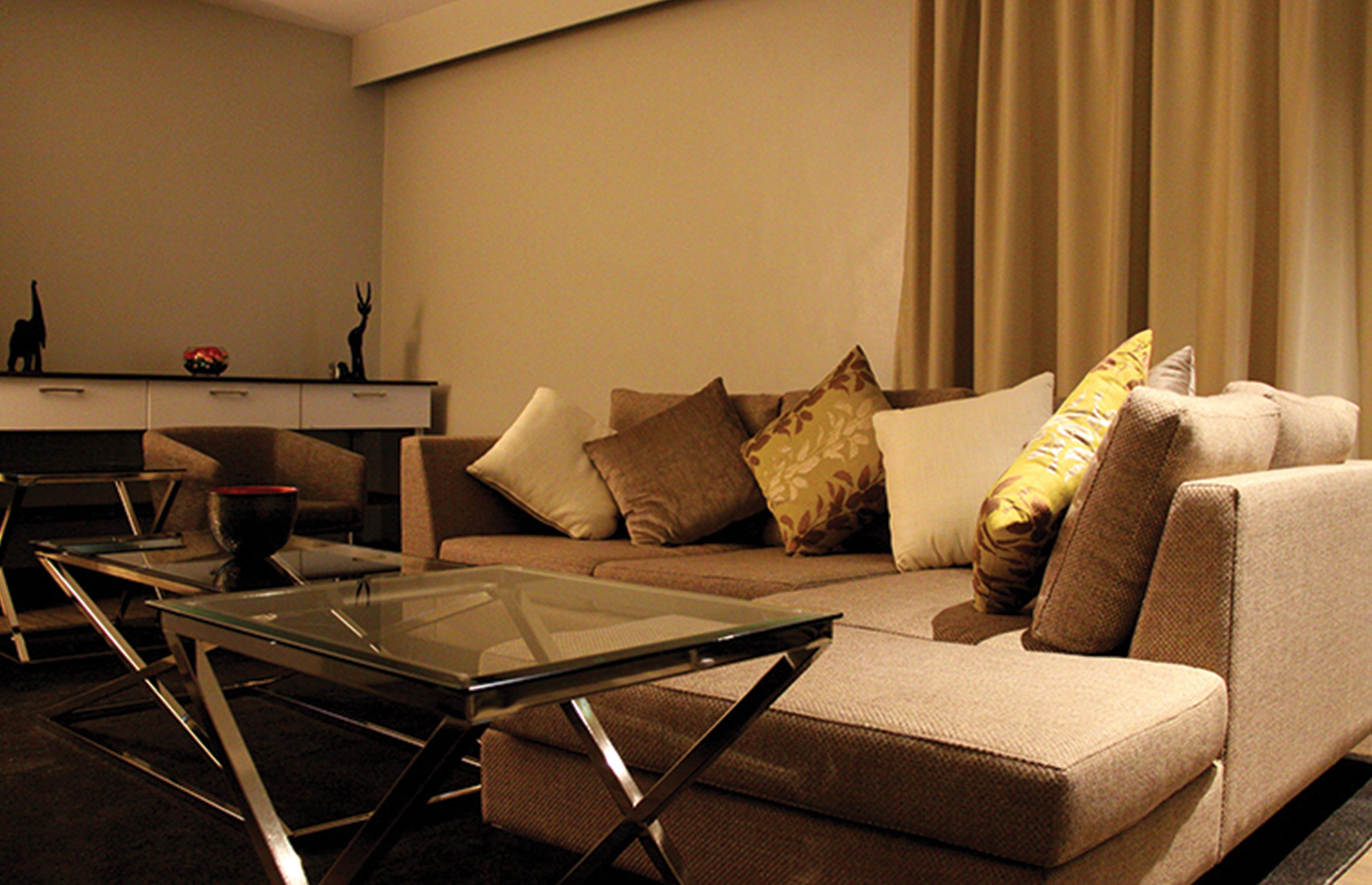 A modern living room with a sofa, a glass coffee table, and a desk with decorative items.