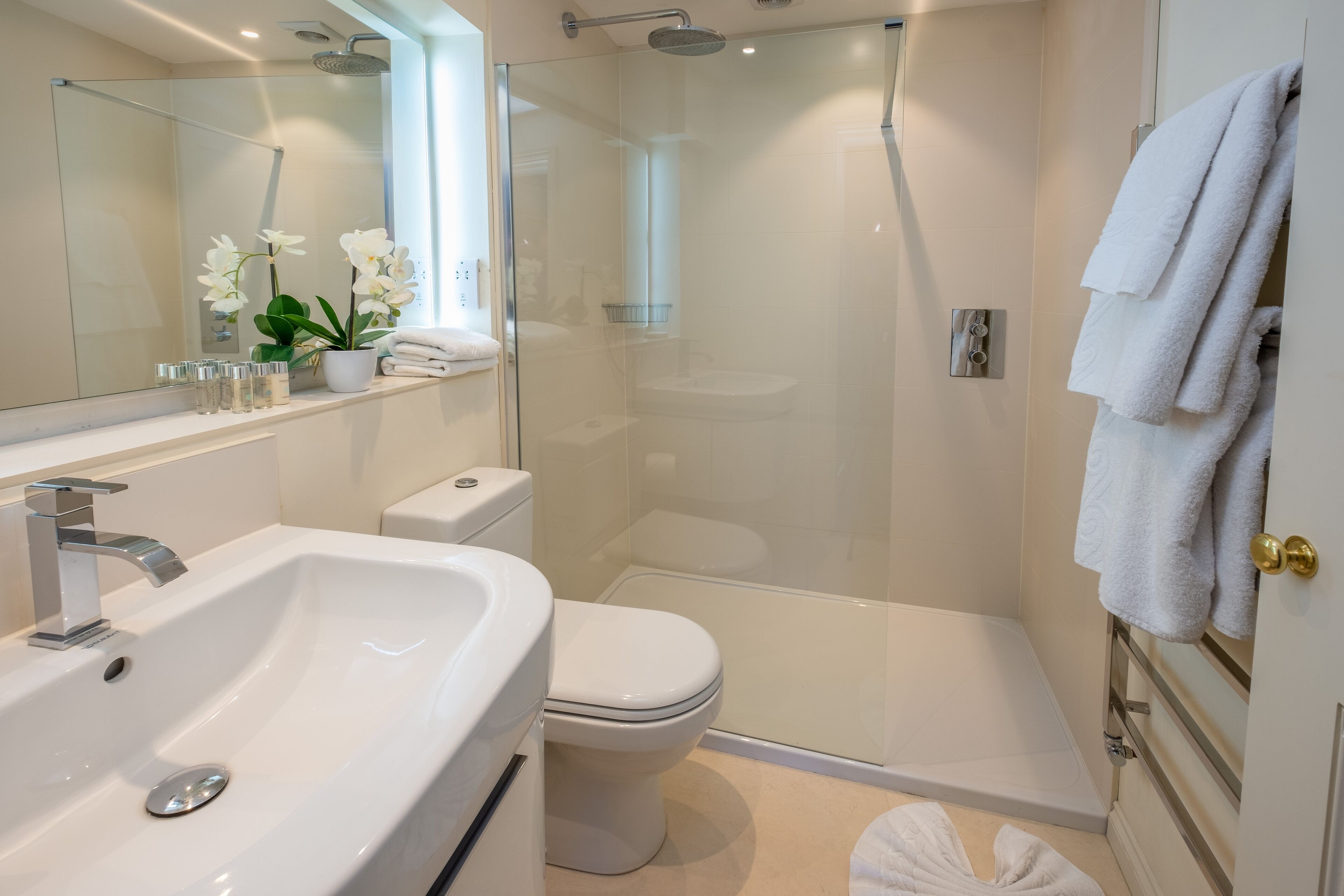 Un baño moderno con ducha de vidrio, lavamanos blanco y retrete.