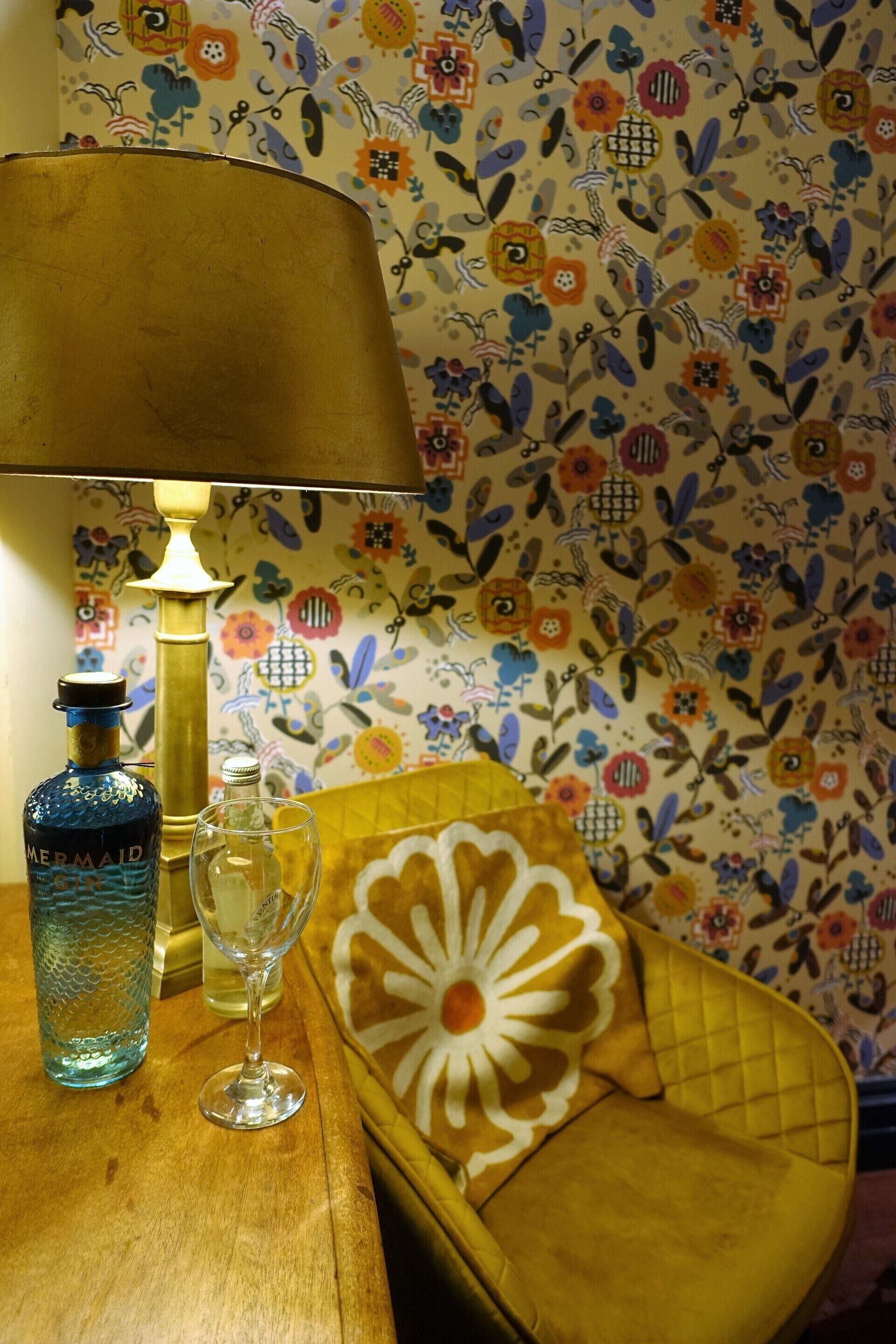 Una mesa con una lámpara, una botella y un vaso.