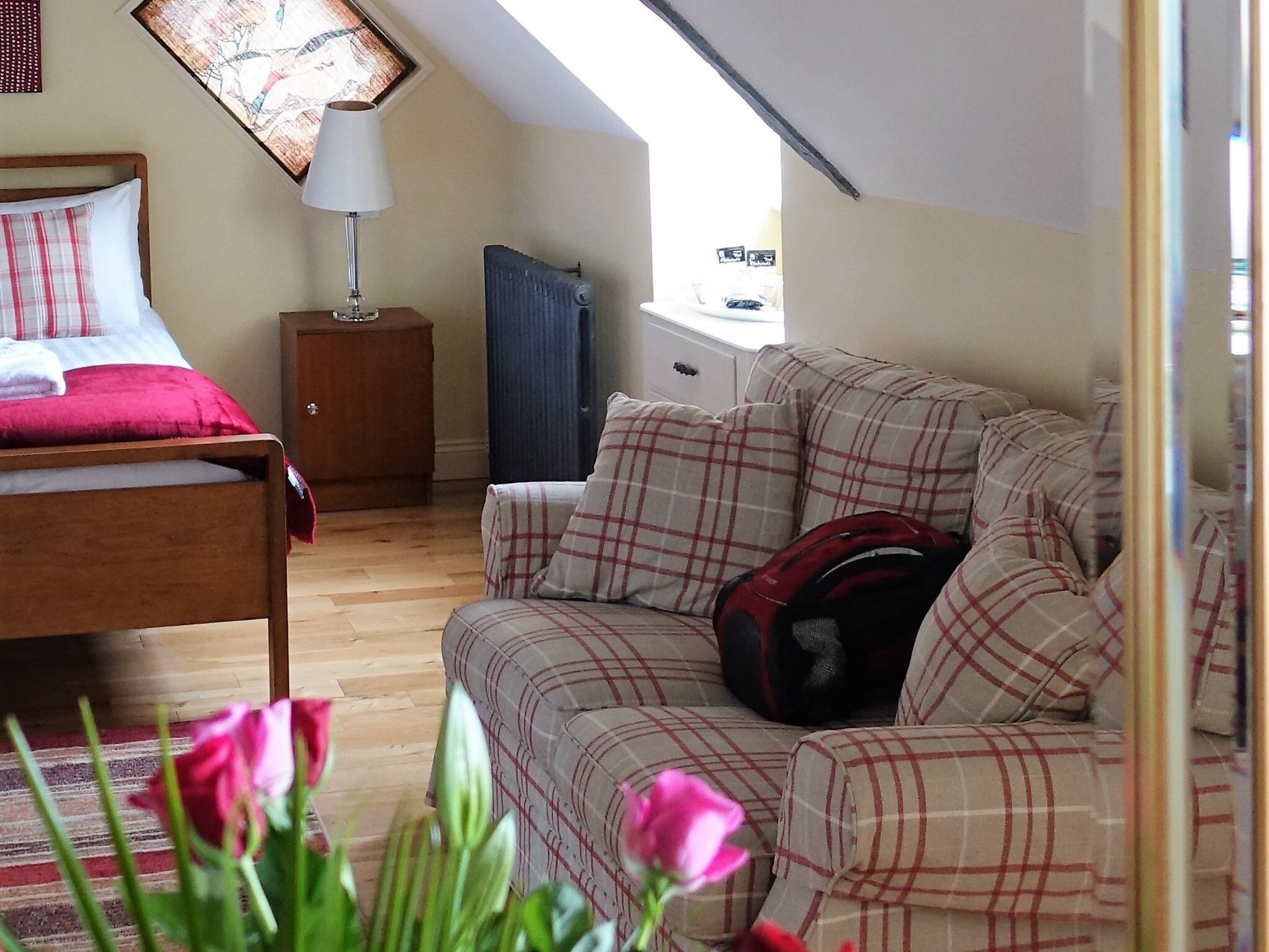 A cozy bedroom with a bed, a nightstand, a radiator, and a window.