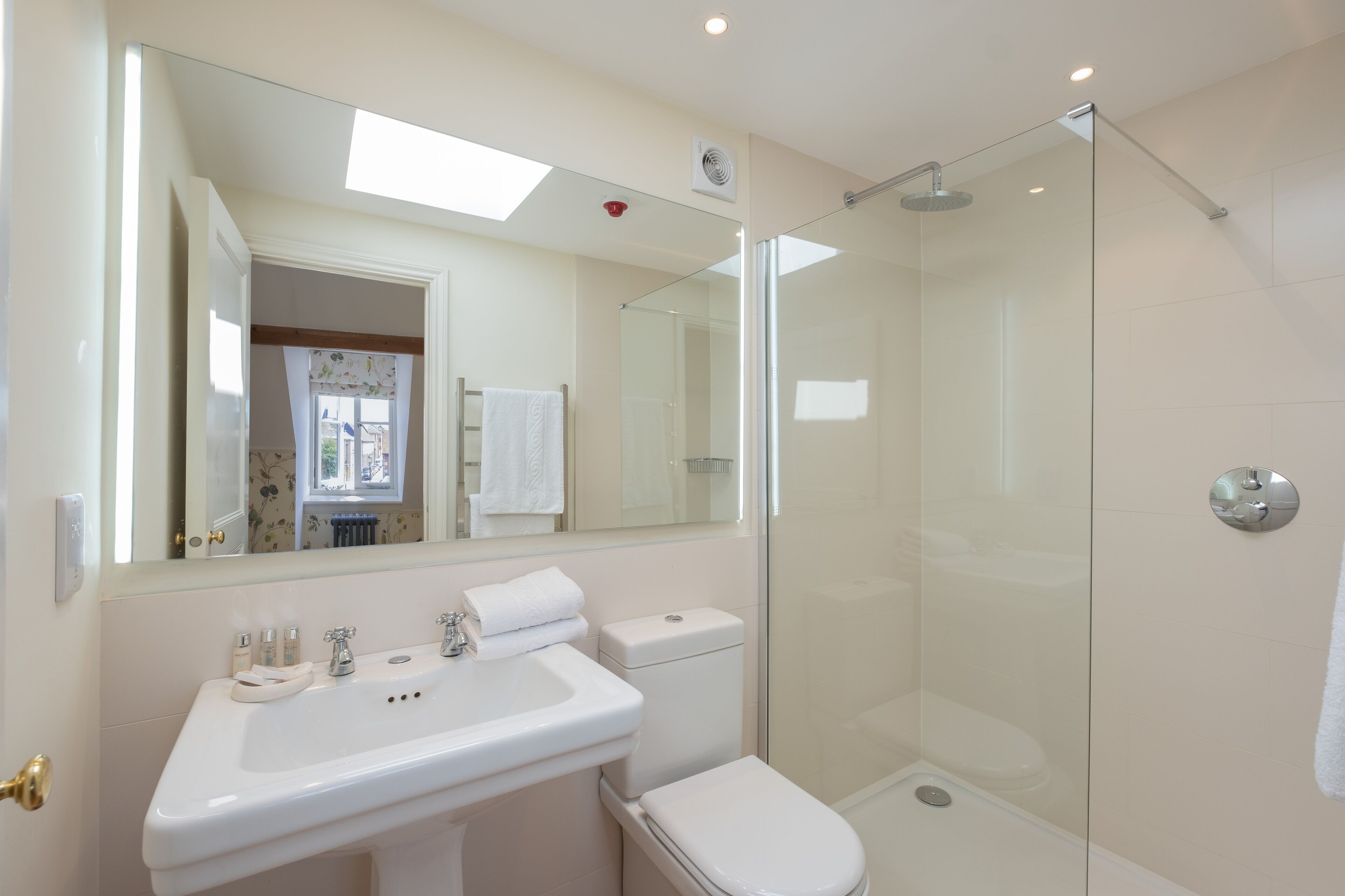 A bathroom with a glass-enclosed shower, a white sink, and a toilet.