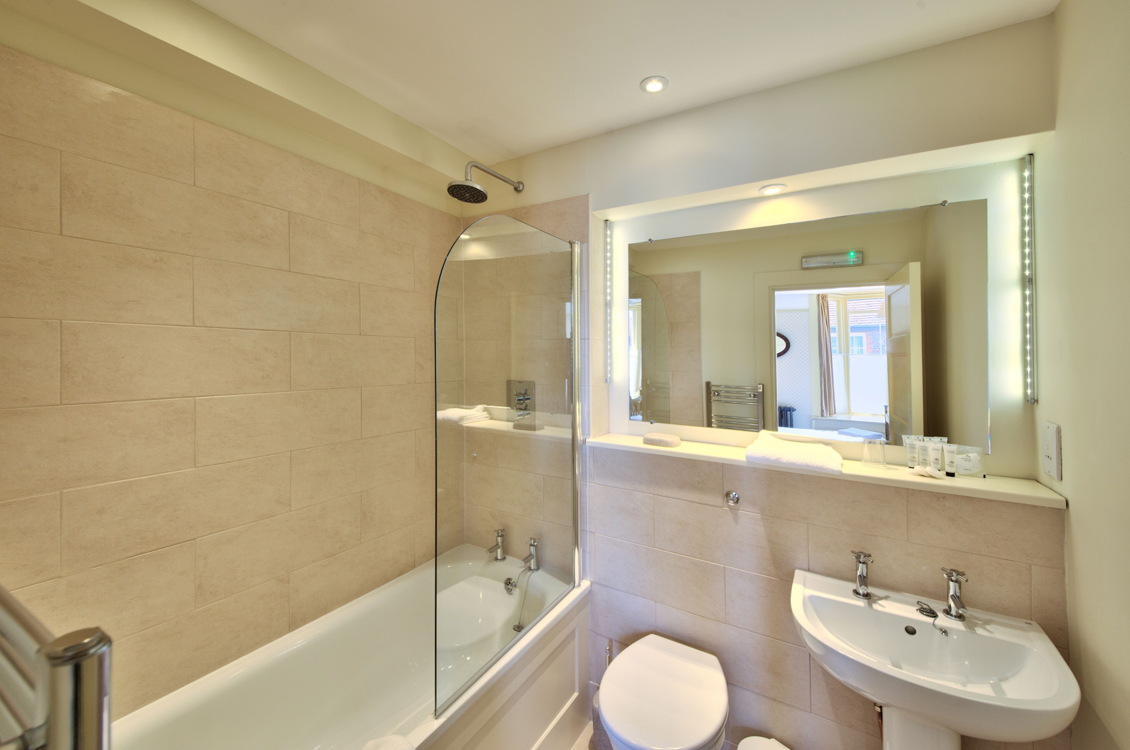 A modern bathroom with a glass-enclosed shower, a bathtub, a toilet, and two sinks.