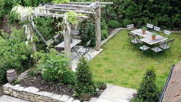 En gårdhave med pergola, sten trapper og et bord med stole.