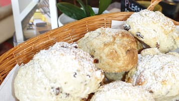 A basket of pastries on a table with a sign that says "Please."