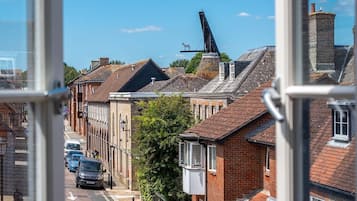 A residential street with brick houses, a wind turbine, and parked cars.