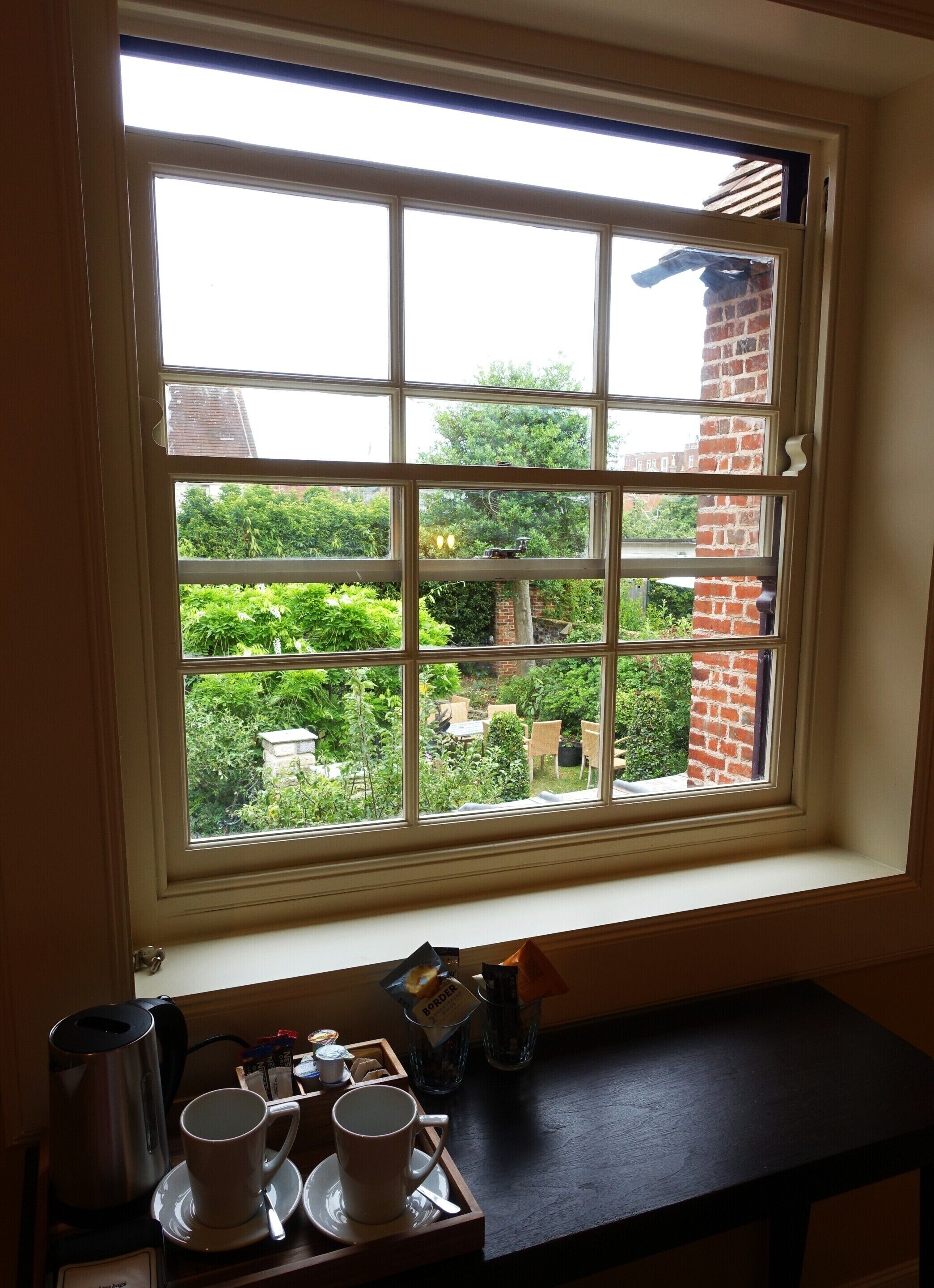 Ein Fenster mit Blick auf einen Garten und eine Ziegelmauer.