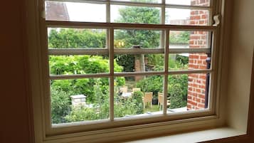 Ein Fenster mit Blick auf einen Garten und eine Ziegelmauer.