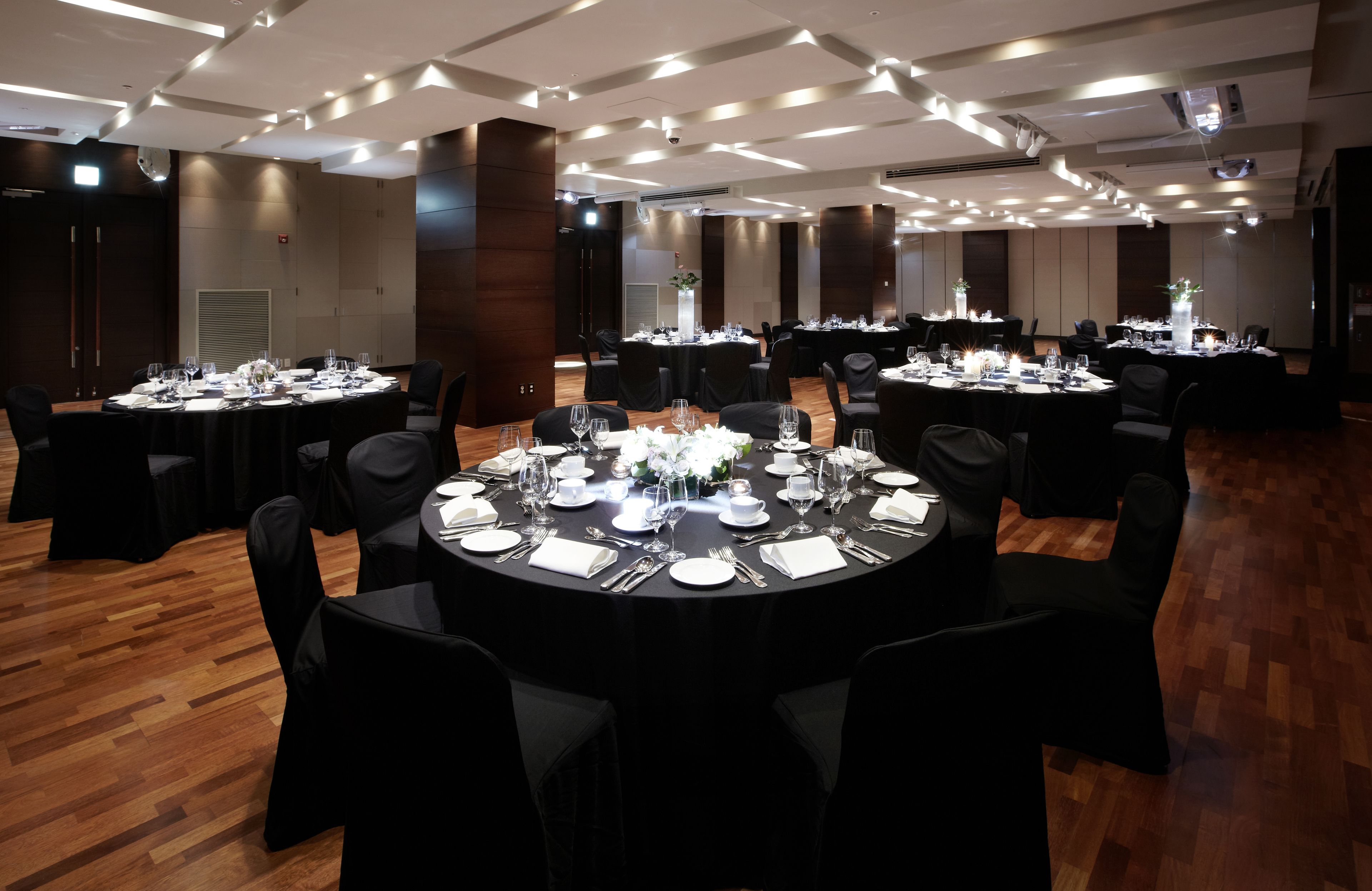 Un salón de conferencias con varias mesas redondas dispuestas para comer, equipado con sillas, mesas y vajilla.