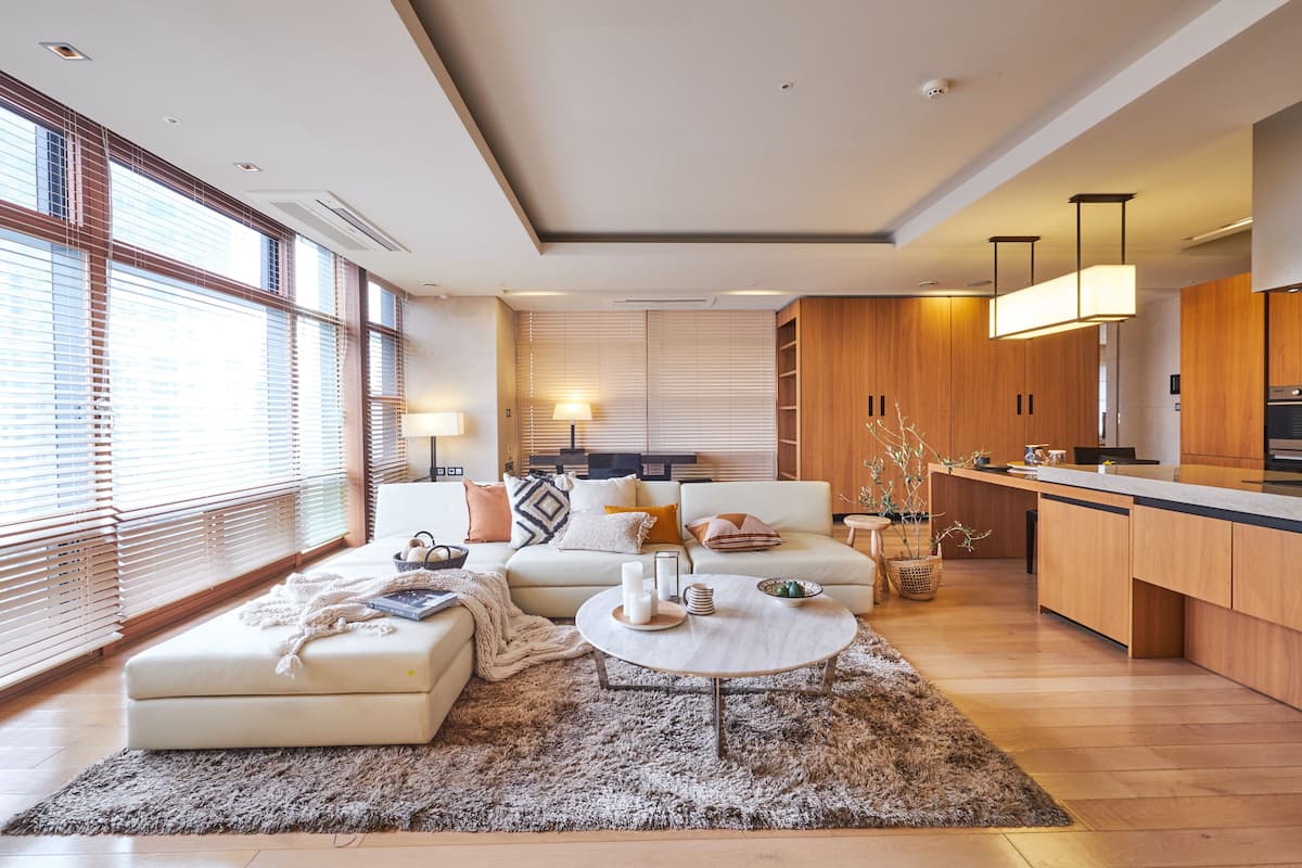 A modern living room with a sofa, coffee table, and a kitchen area with wooden cabinets and a countertop.