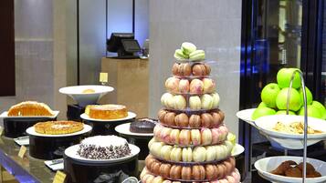 A buffet with various desserts and a tiered display of macarons.