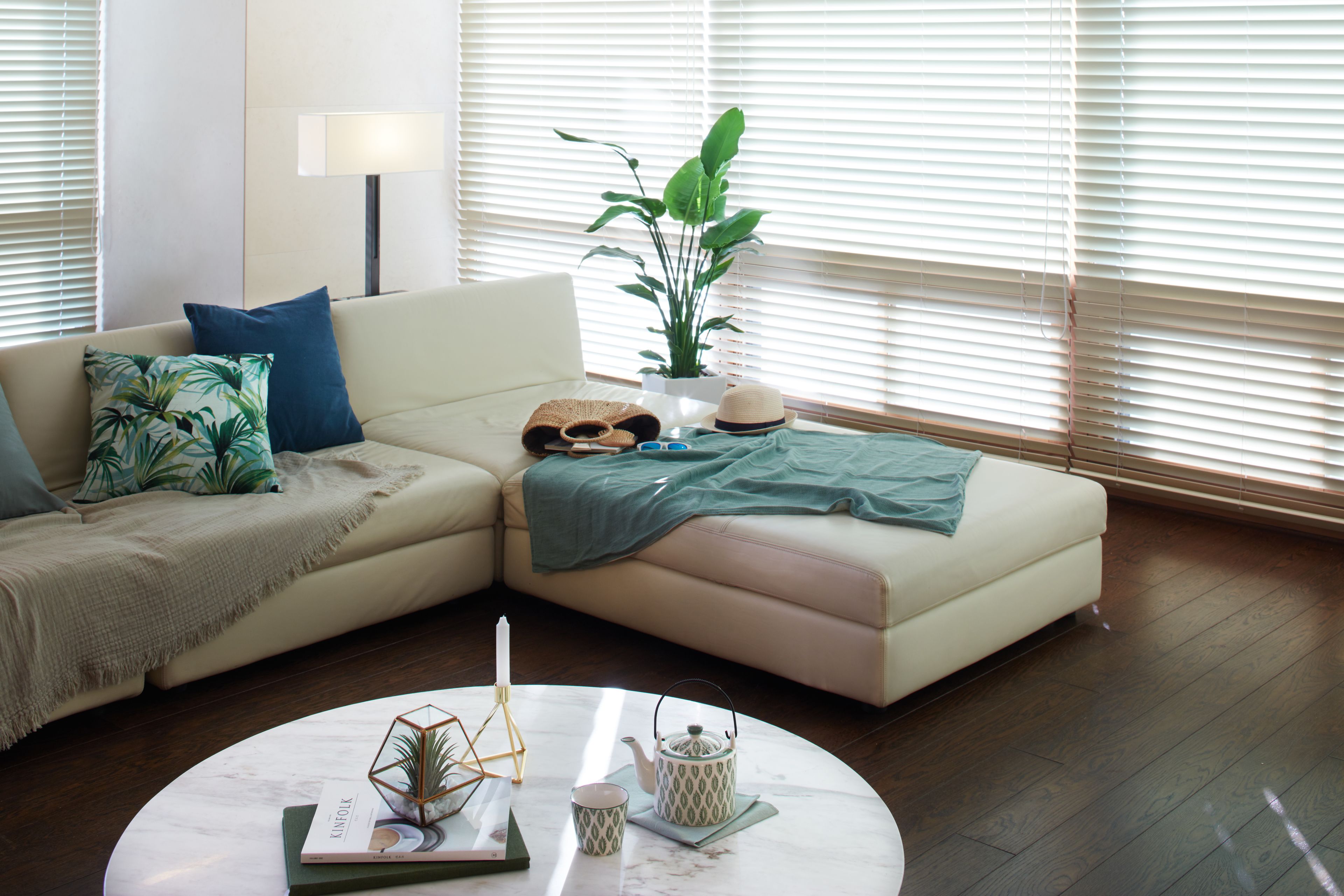 Una sala de estar moderna con un sofá seccional color beige, una mesa redonda de centro y una planta en maceta.