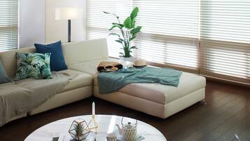 Una sala de estar moderna con un sofá seccional color beige, una mesa redonda de centro y una planta en maceta.