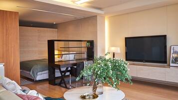 A modern living room with a sofa, coffee table, TV, and a small bookshelf.