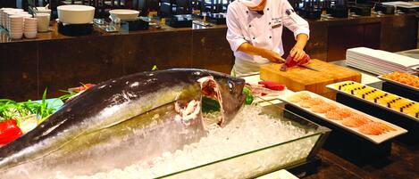 A seafood display with a large fish on ice, a chef preparing food, and various seafood dishes.